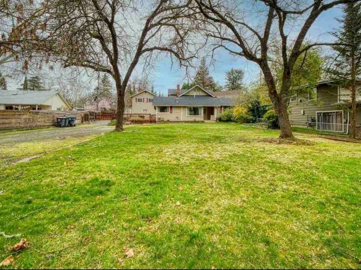 A wide front lawn bordered by mature trees, with the house in the background. The open grassy area is perfect for family gatherings and outdoor games, evoking a sense of community, play, and seasonal celebrations.