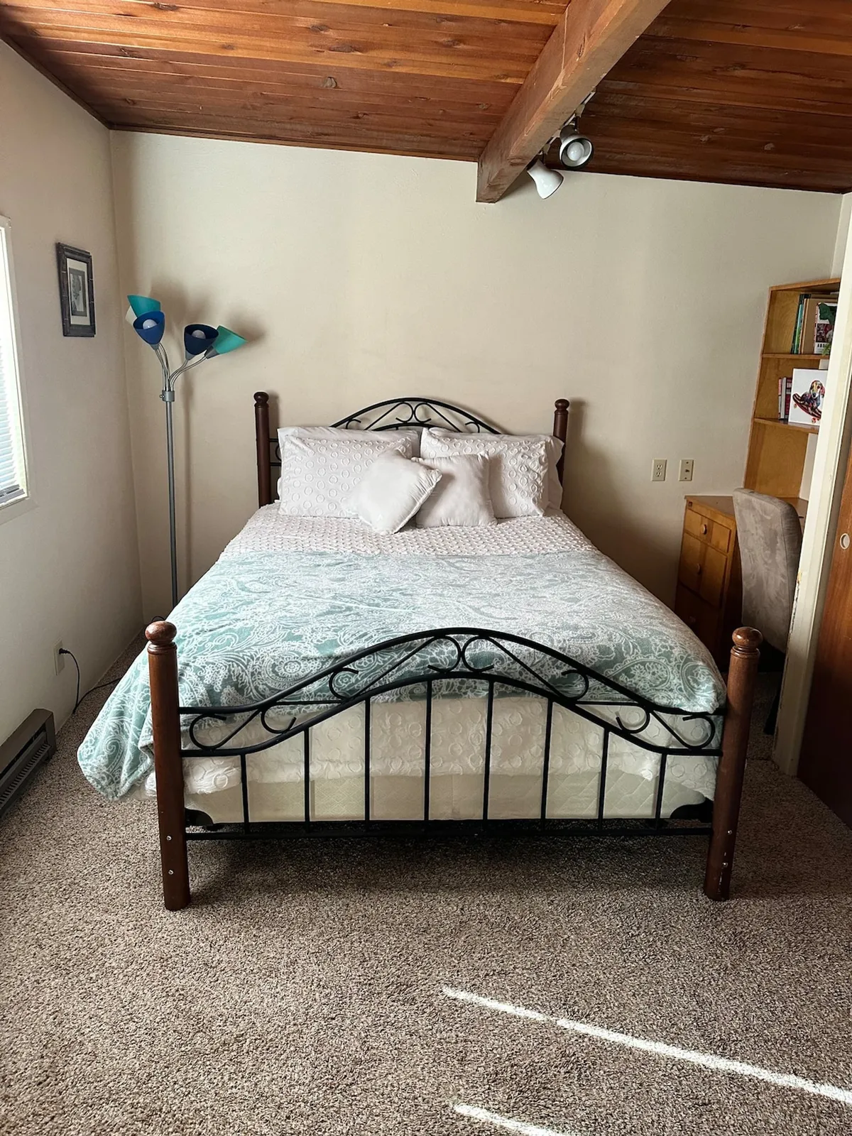 A cozy bedroom with a comfortable bed, a bedside lamp for nighttime reading, and a bookshelf stocked with books. The decor is warm and inviting, creating a perfect hideaway for rest and peaceful solitude.