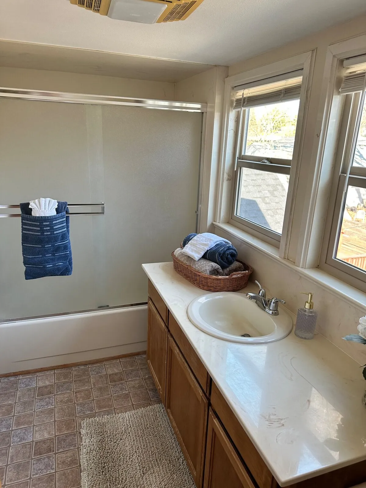 A spa-inspired bathroom with a modern sink, a walk-in shower, fresh towels, and a window that lets in natural light. The space is bright, airy, and inviting—a perfect spot for unwinding with a refreshing shower or bath.