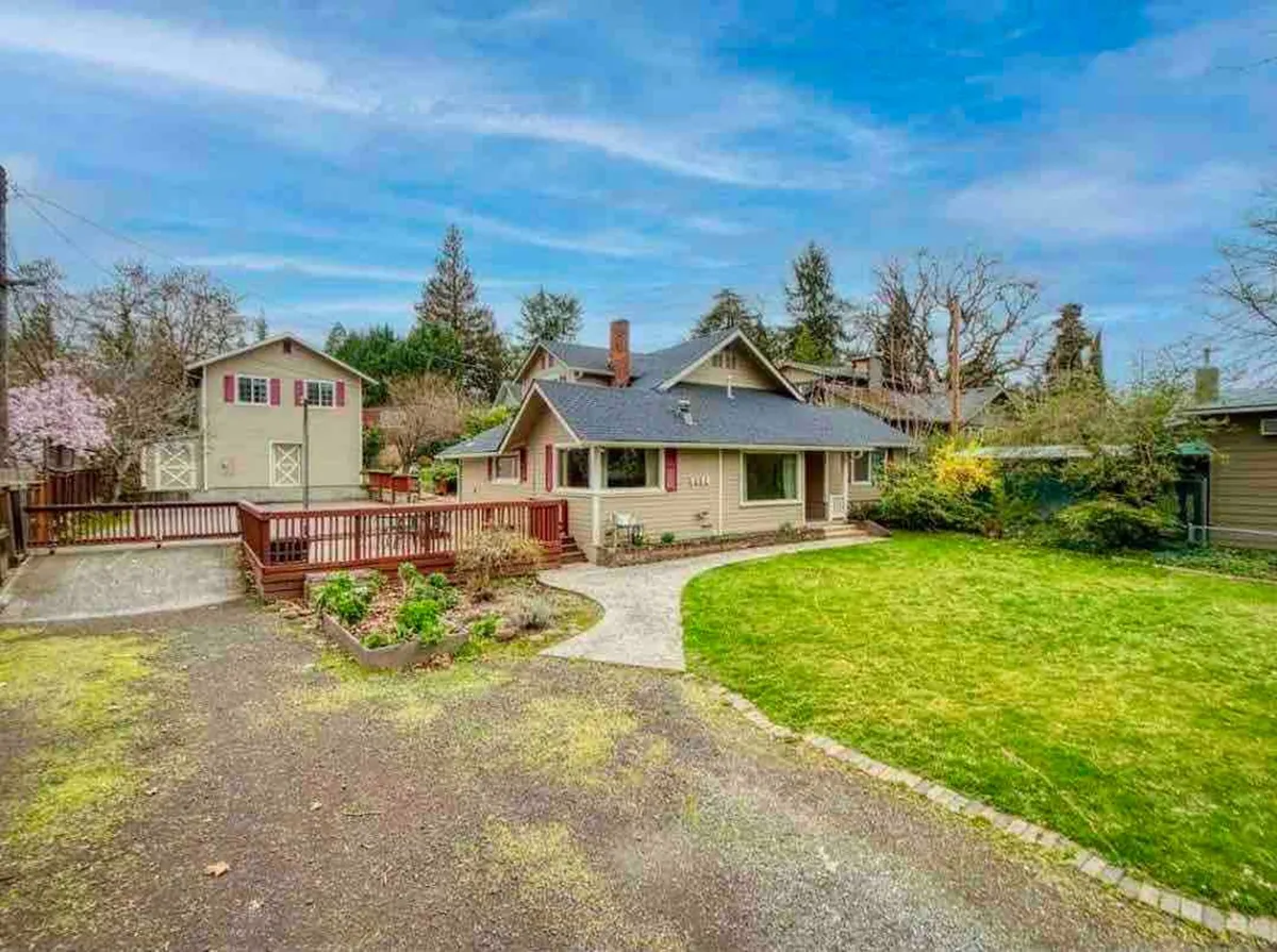 The hero image showcases the main house with its inviting patio and lush garden area, bathed in the warm glow of a sunset. The deck is set up for outdoor dining and relaxation, with the outbuilding and vibrant landscaping hinting at ample space for family gatherings and unwinding under the stars.