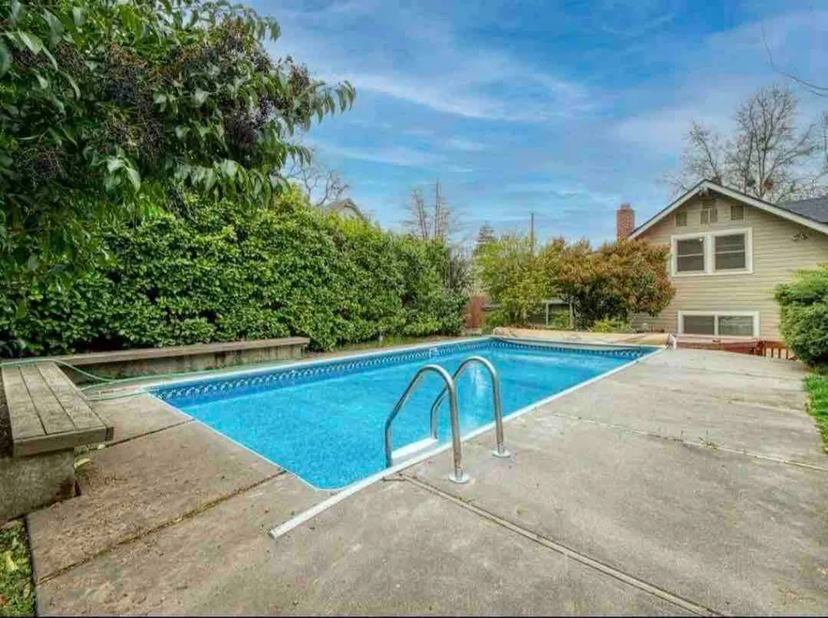 This exterior shot highlights the sparkling swimming pool framed by lush greenery and an expansive deck area. Lounge chairs invite guests to relax, while the pool itself suggests opportunities for unwinding and informal socializing after structured sessions.