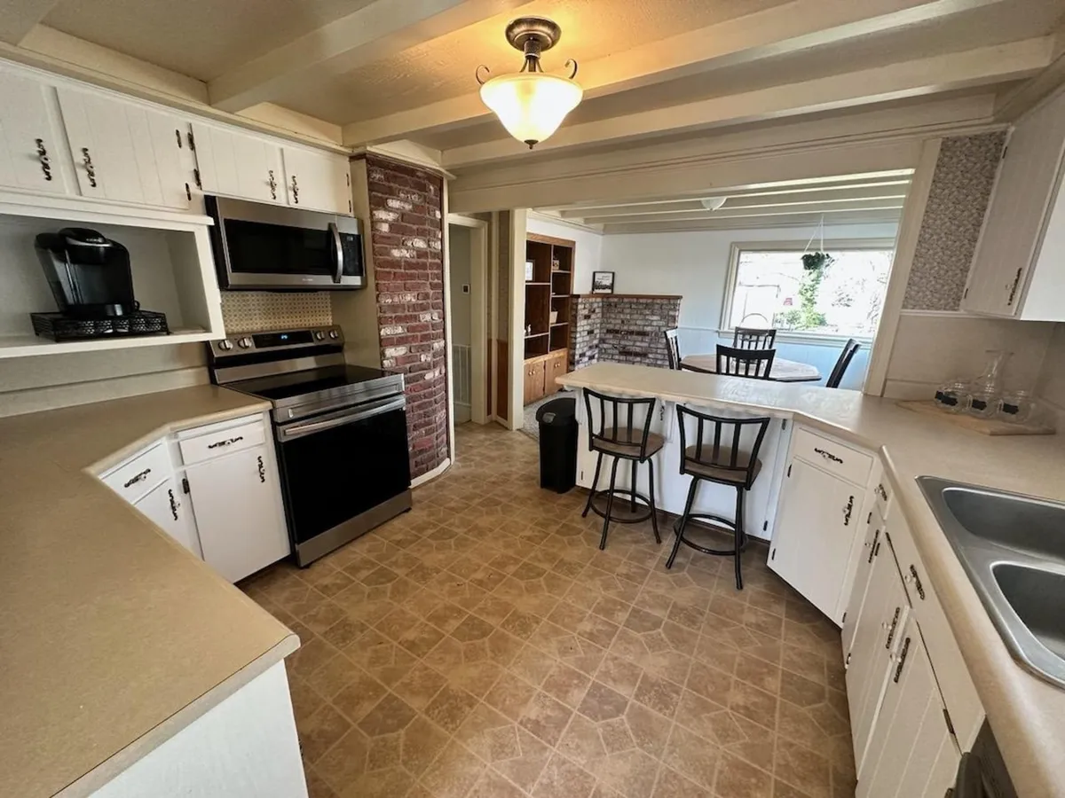 A chef-inspired kitchen featuring stainless steel appliances, a brick accent wall, and a spacious island with seating for informal gatherings or meal prep. The room exudes warmth and functionality, inviting both cooking and socializing.